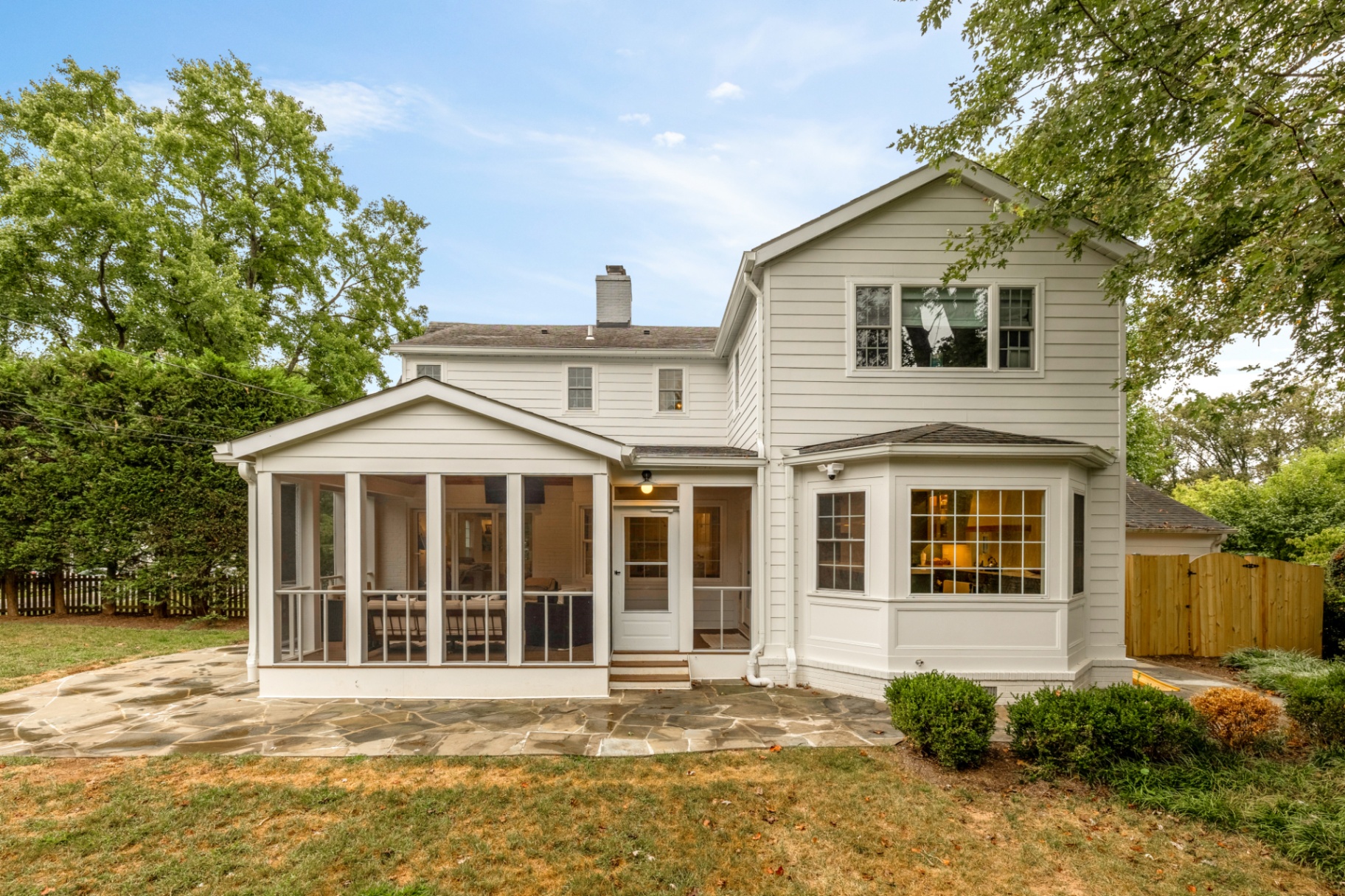 Rear exterior of a renovated home with screened porch and bay window addition