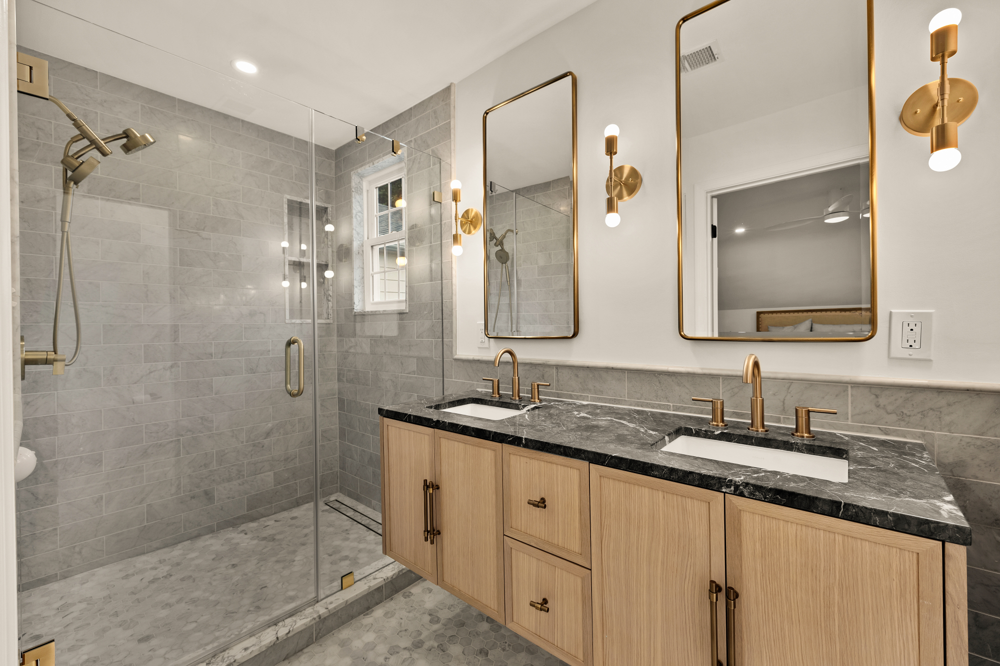 Primary bathroom with marble tile, walk-in glass shower and brass fixtures