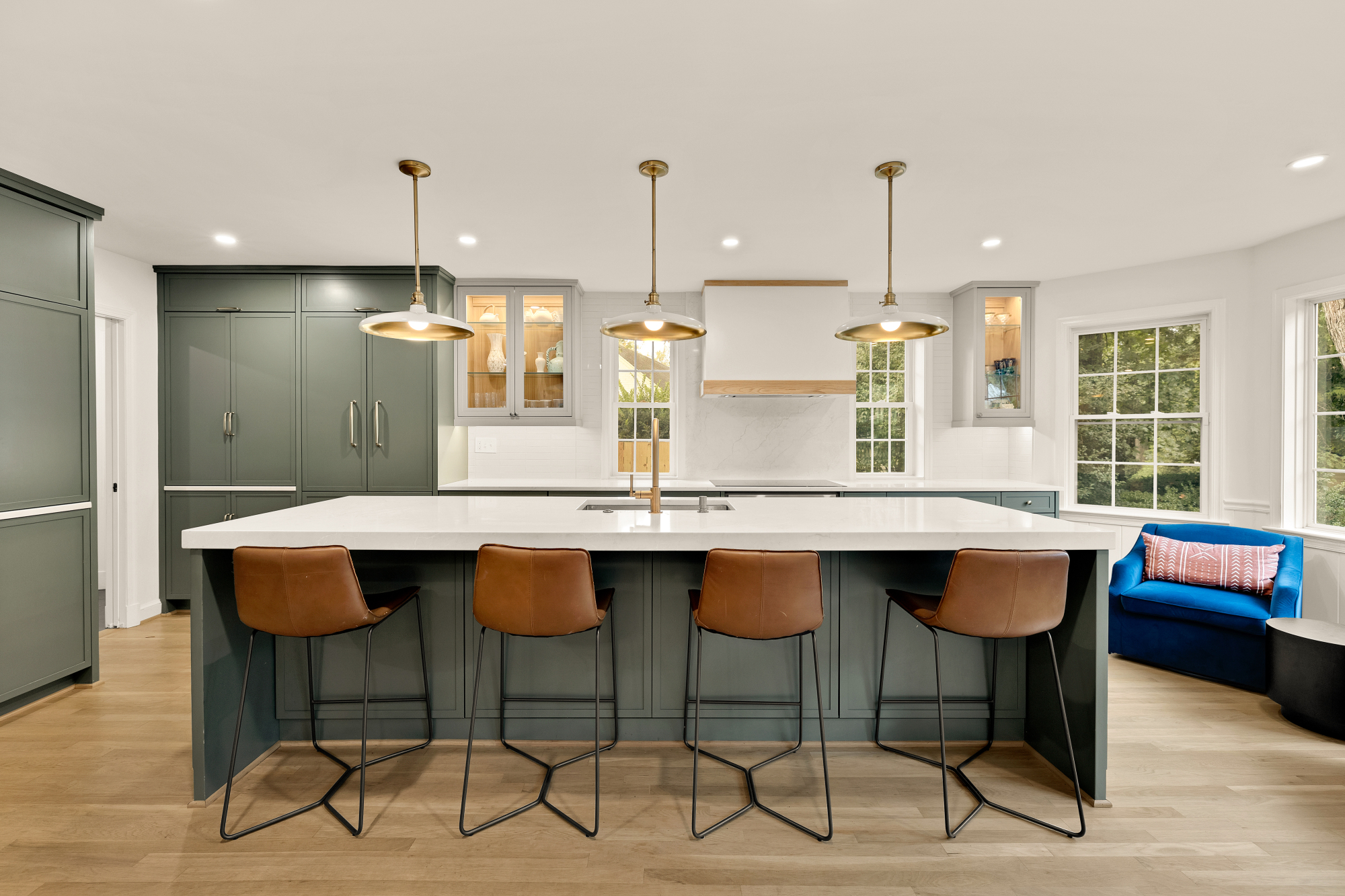 Modern kitchen with sage-green cabinetry, white quartz island and brass pendant lighting